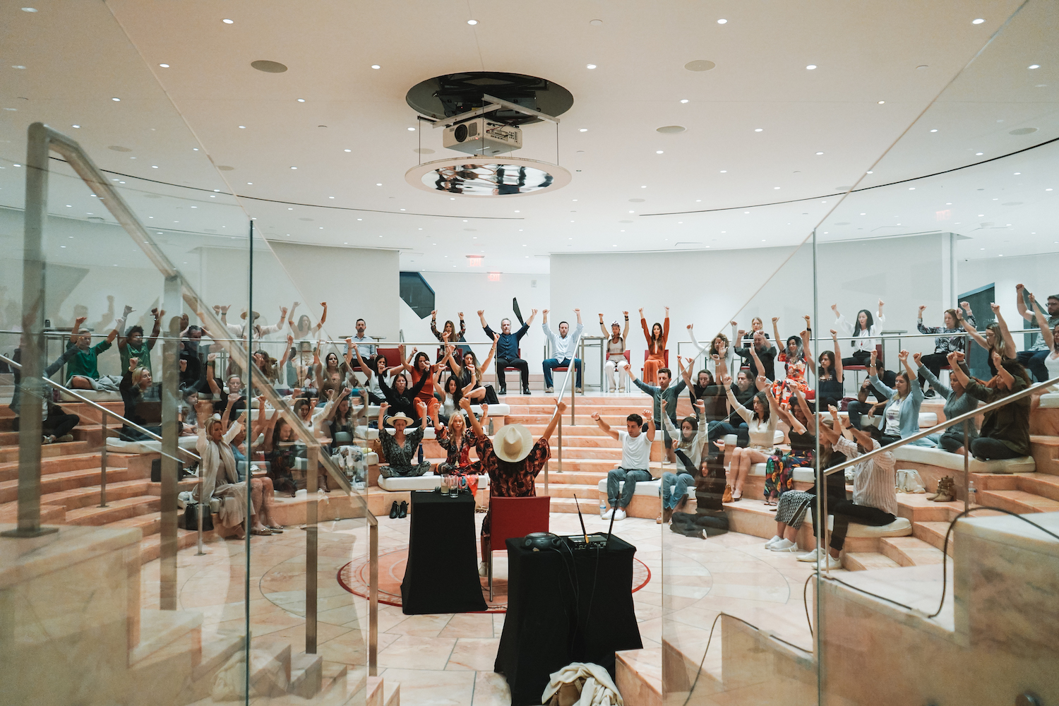 The Modern ŌM community raising their arms together during a guided session in a Miami amphitheater